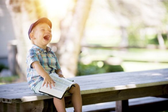 Happy child holding a book outdoors